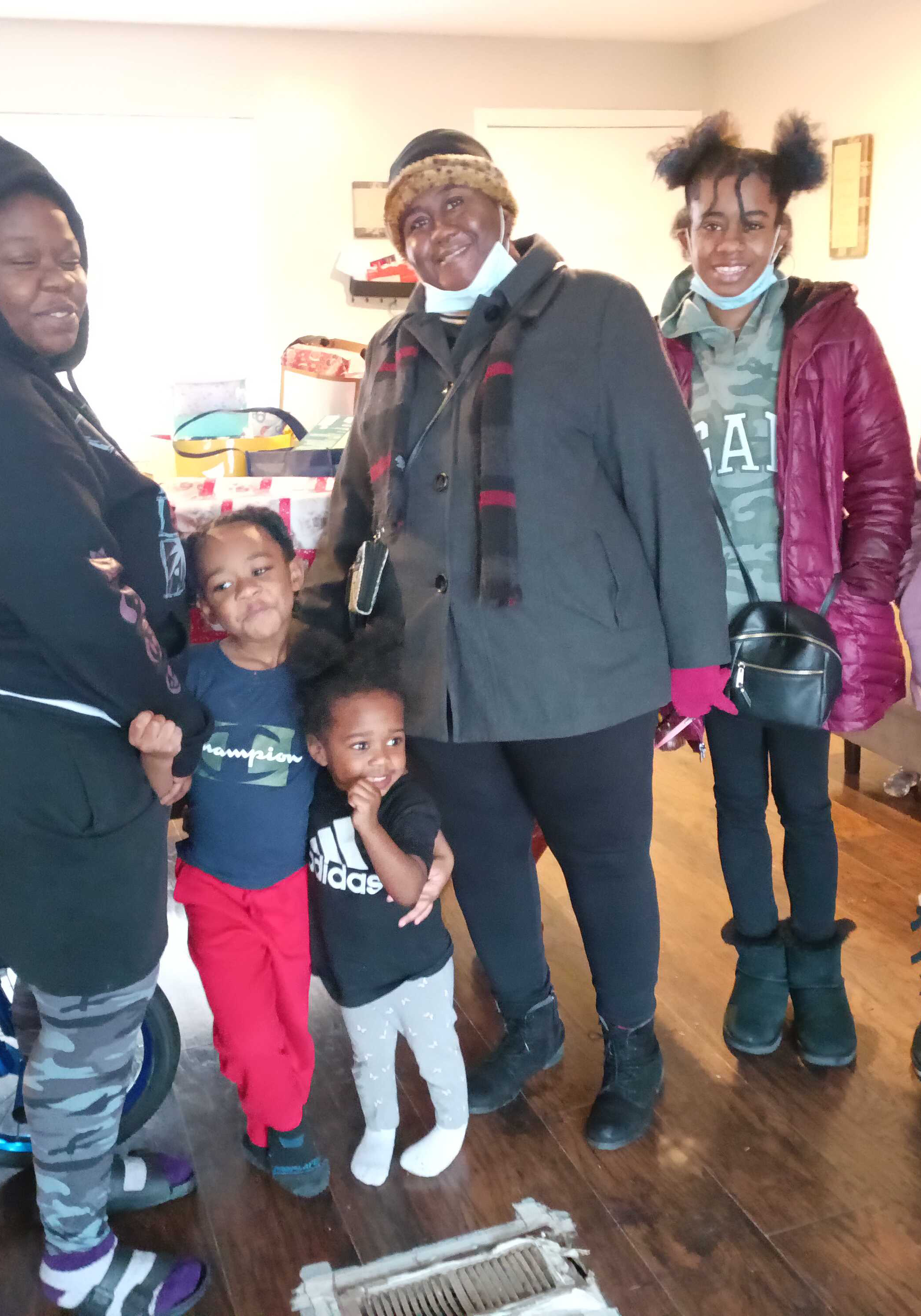 Six people standing in a living room in winter coats