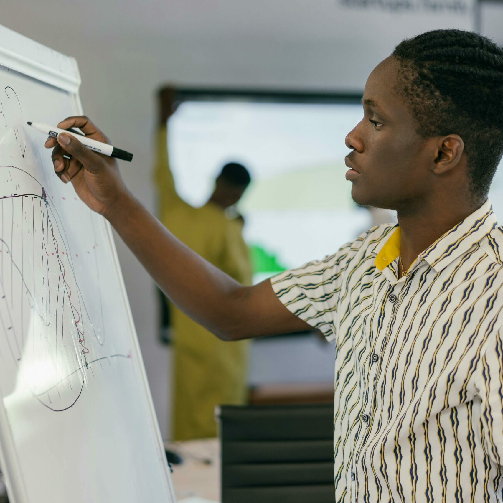 A man drawing a diagram on a whiteboard in an office