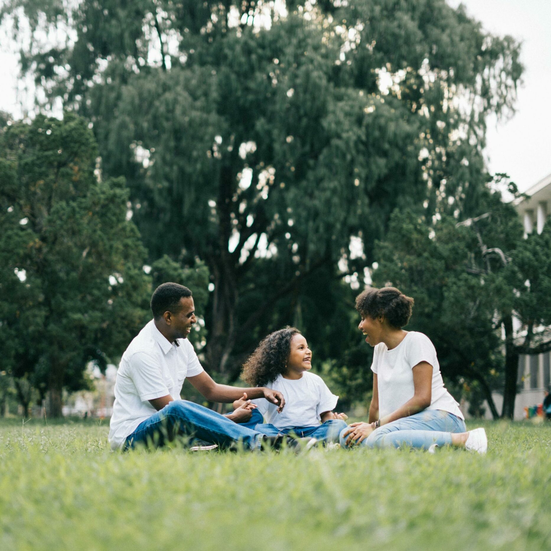 A family sitting outside on grass laughing together.