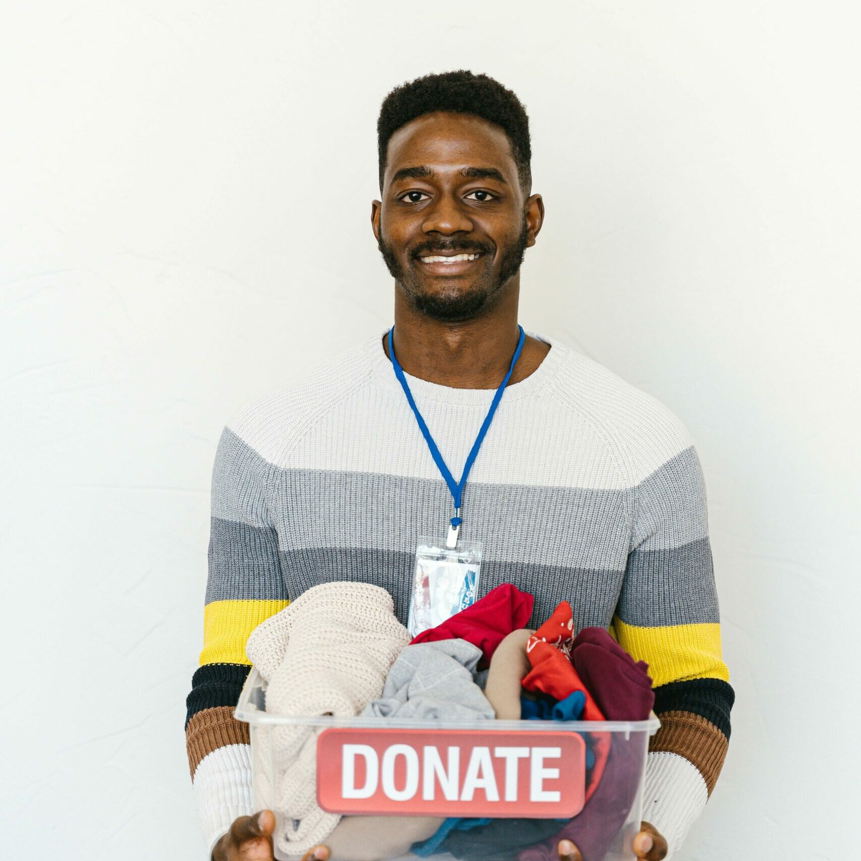 Man holding a donation bin full of clothes