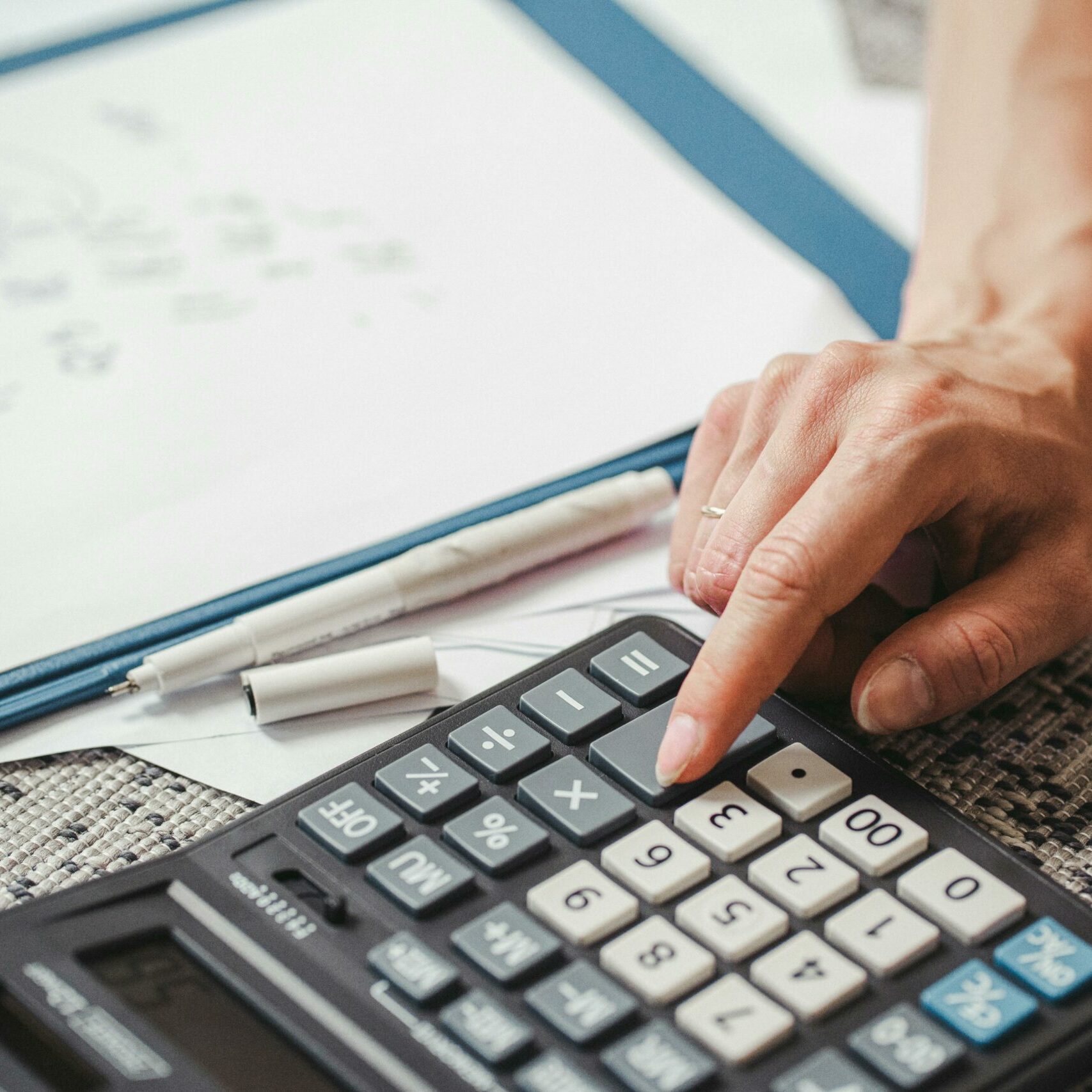 A hand pressing a button on a calculator